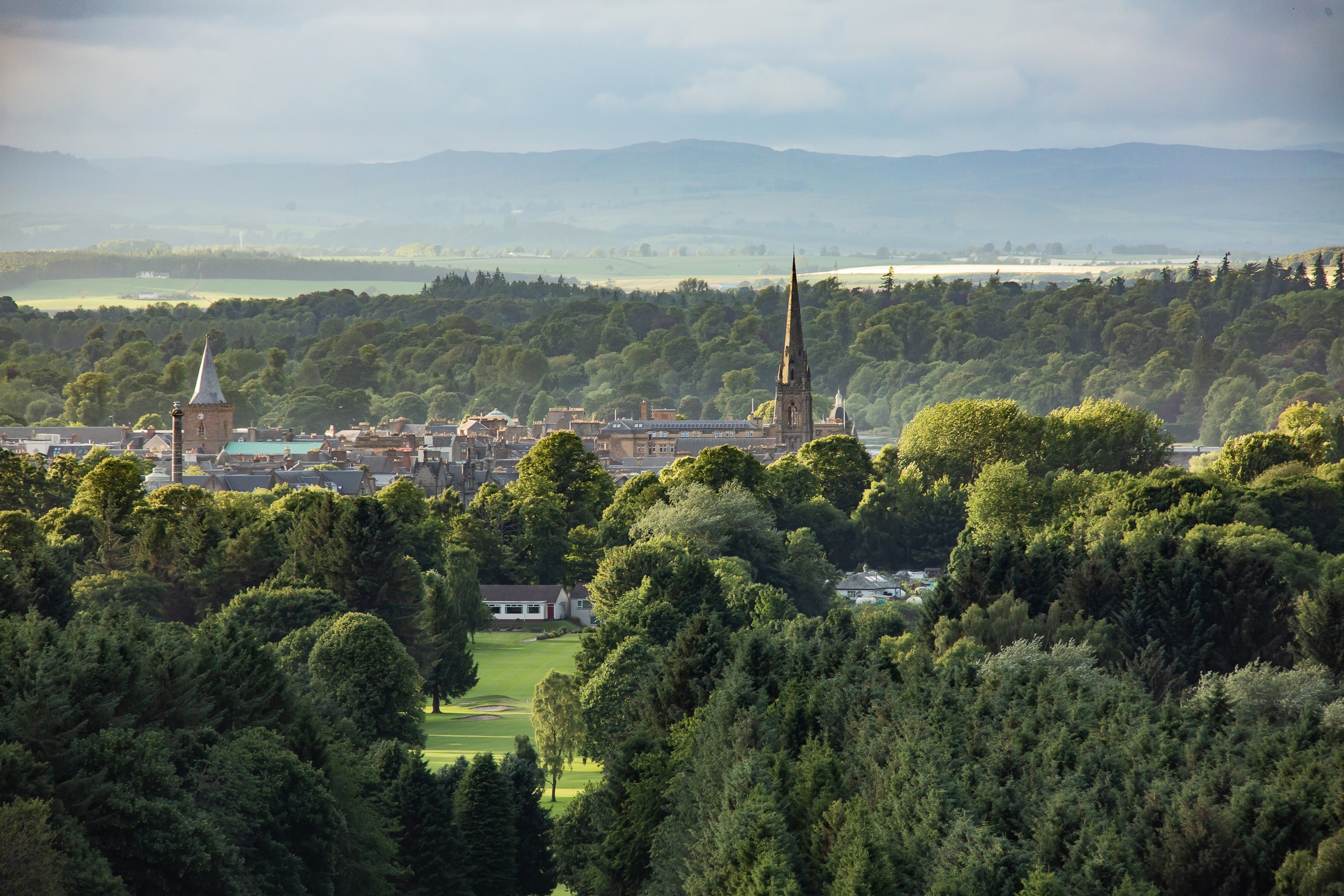 Smuk udsigt over historisk by med kirketårne omgivet af frodig grøn natur og bakkelandskab