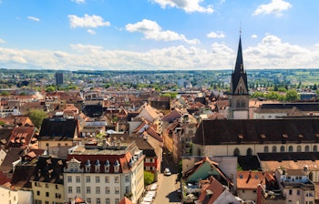 Luftfoto af historisk europæisk by med kirketårn og traditionelle røde tegltage under blå himmel