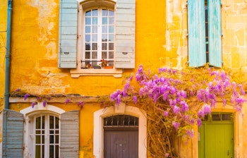 Idyllisk smal gade med blomstrende lilla blåregn i det historiske centrum af Arles i Provence, Frankrig