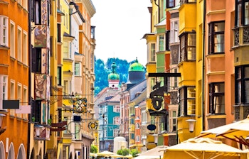 Farverige historiske bygninger langs gaden i Innsbruck med smukke Alperne i baggrunden, Tirol i Østrig