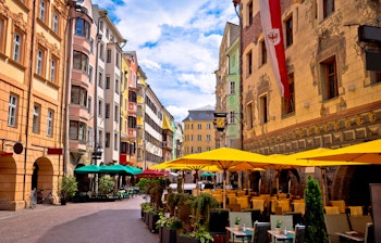 Farverige historiske bygninger langs en charmerende gade i Innsbruck med de majestætiske alper i baggrunden, Tyrol, Østrig