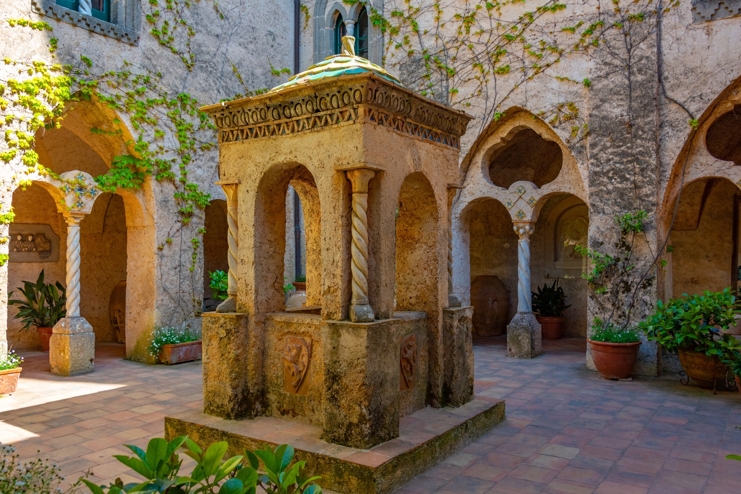 Historisk italiensk klostergård med middelalderarkitektur og ornamentale stenbuer