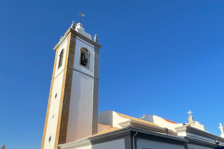 Smuk historisk kirke med klokketårn i Albufeiras gamle bydel, Algarve, Portugal omgivet af traditionel portugisisk arkitektur