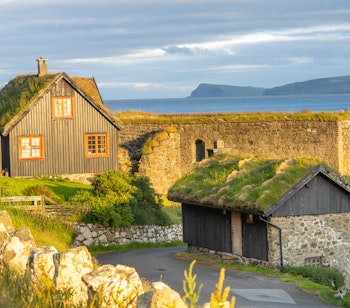 Den historiske Kirkjubøargarður gård i Kirkjubøur, beboet siden 1100-tallet, med traditionel færøsk arkitektur, sorte træfacader og græstag på Streymoy