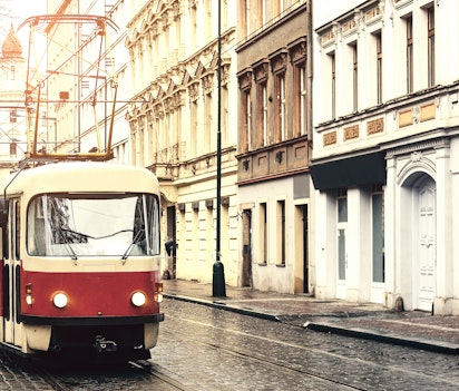 Historisk sporvogn kører gennem charmerende europæisk bydel med brosten og klassisk arkitektur