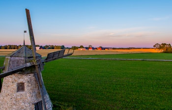Historisk vindmølle med udsigt over grønne marker i solnedgang på Gotland i Sverige