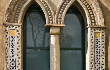 Smukt udskåret stenvindue fra Villa Cimbrone i Ravello med blomsterpotte på den historiske amalfikyst i Italien
