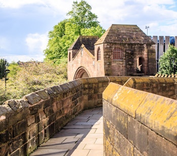Den historiske bymur i Chester med middelalderligt stentårn og gangsti under blå himmel, populær seværdighed i England