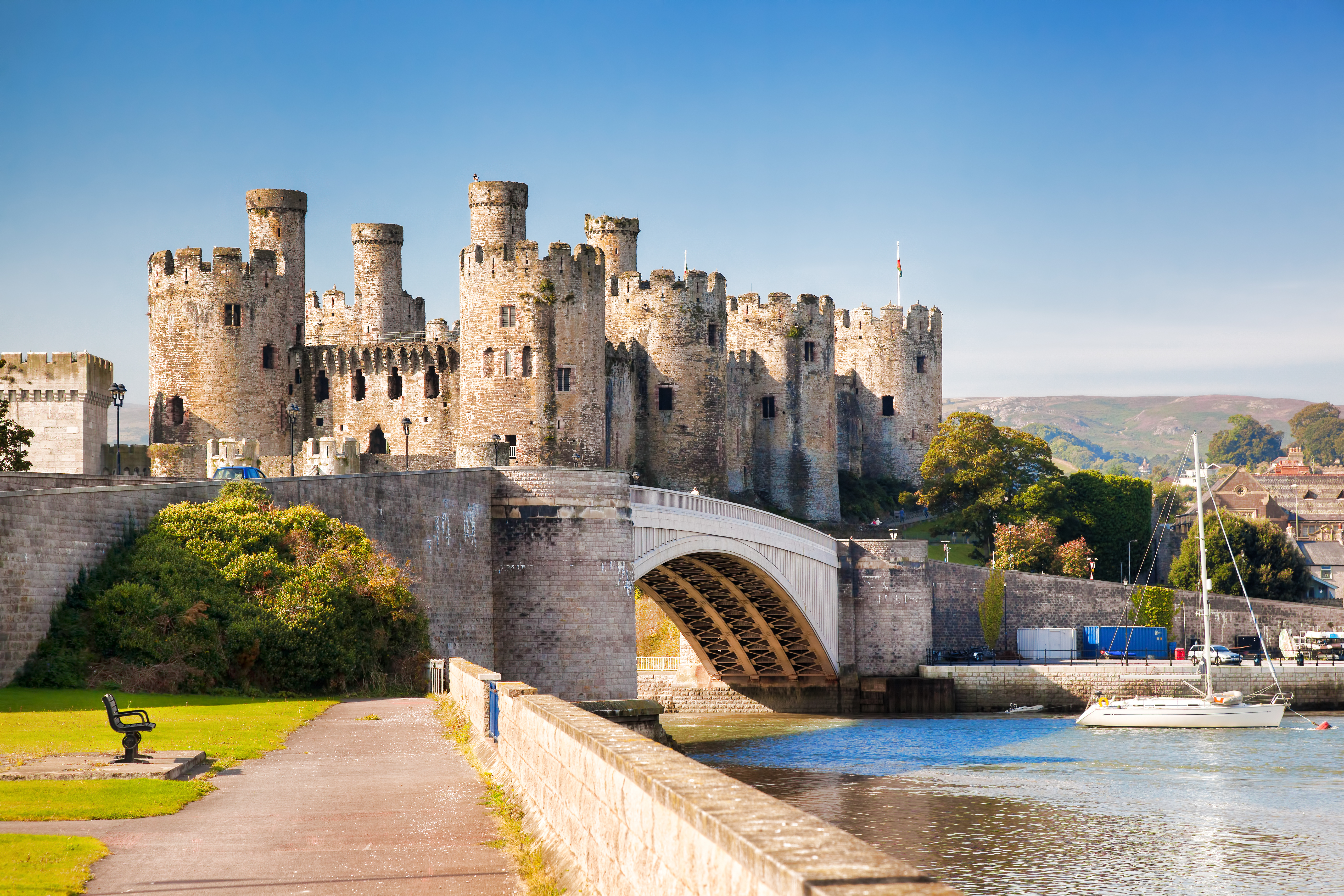 Det majestætiske Conwy slot i Wales med den gamle stenbro over havnen og blå himmel i baggrunden