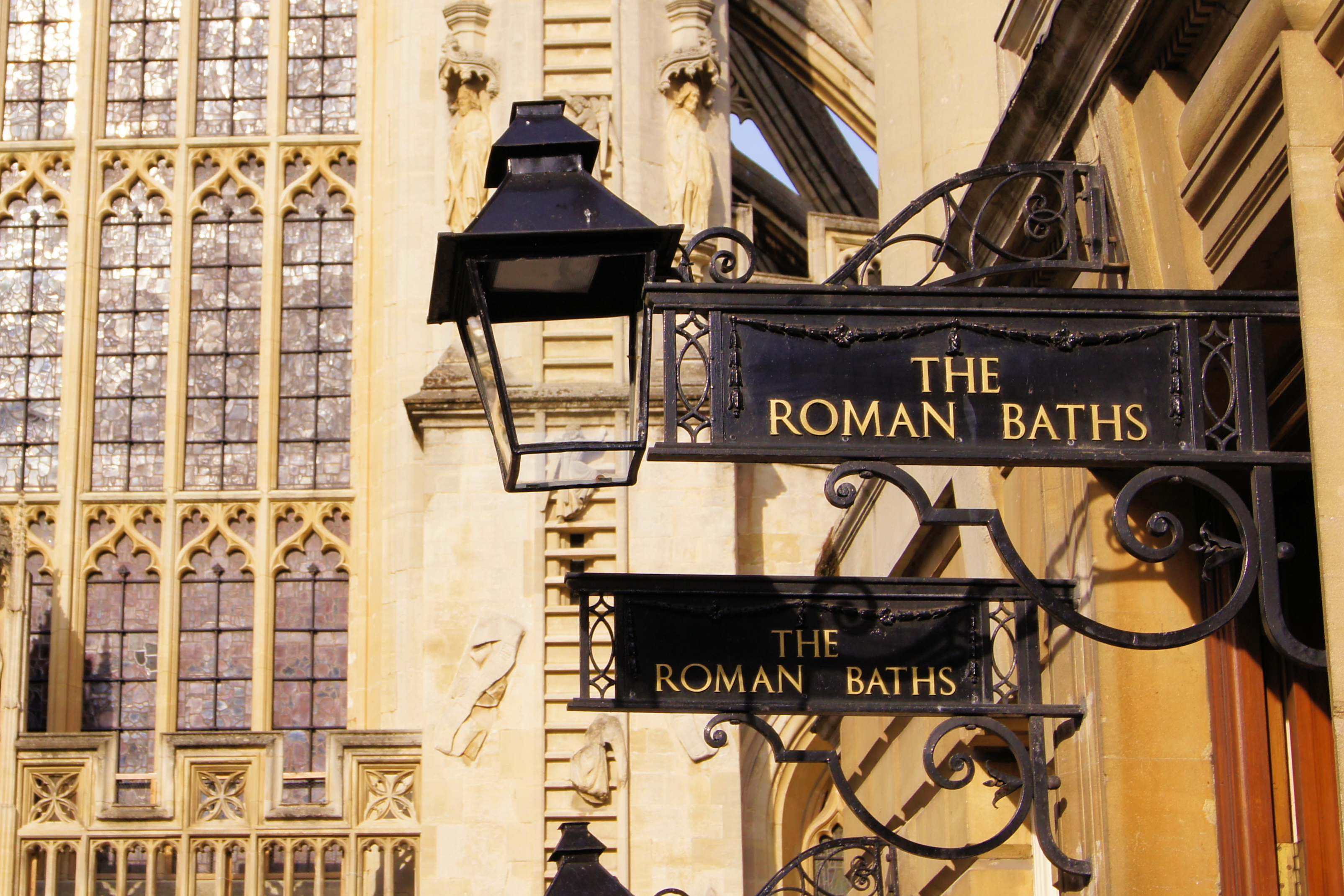 Smukke historiske jernskilte ved de romerske bade i Bath med den gotiske Bath Abbey i baggrunden, Somerset, England