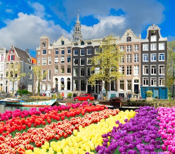 Farverige historiske kanalhuse spejler sig i vandet ved solnedgang i Amsterdam, Holland, perfekt rejsemål for byferie med charmerende arkitektur