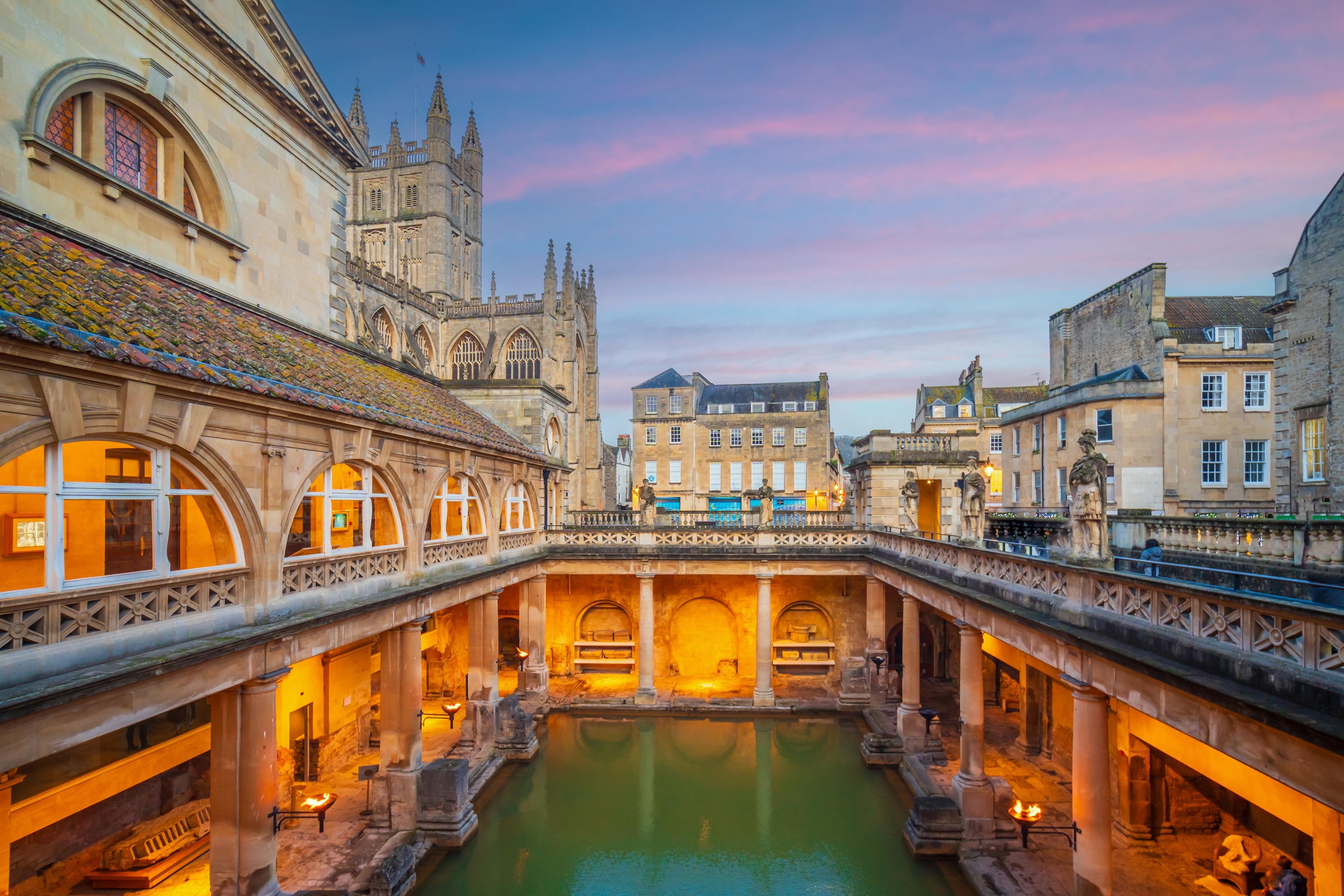 De historiske romerske bade i Bath oplyst ved skumringstid med Bath Abbey i baggrunden, UNESCO verdensarv i England