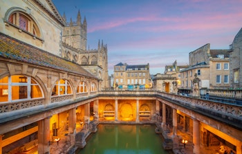 De historiske romerske bade i Bath oplyst ved skumringstid med Bath Abbey i baggrunden, UNESCO verdensarv i England