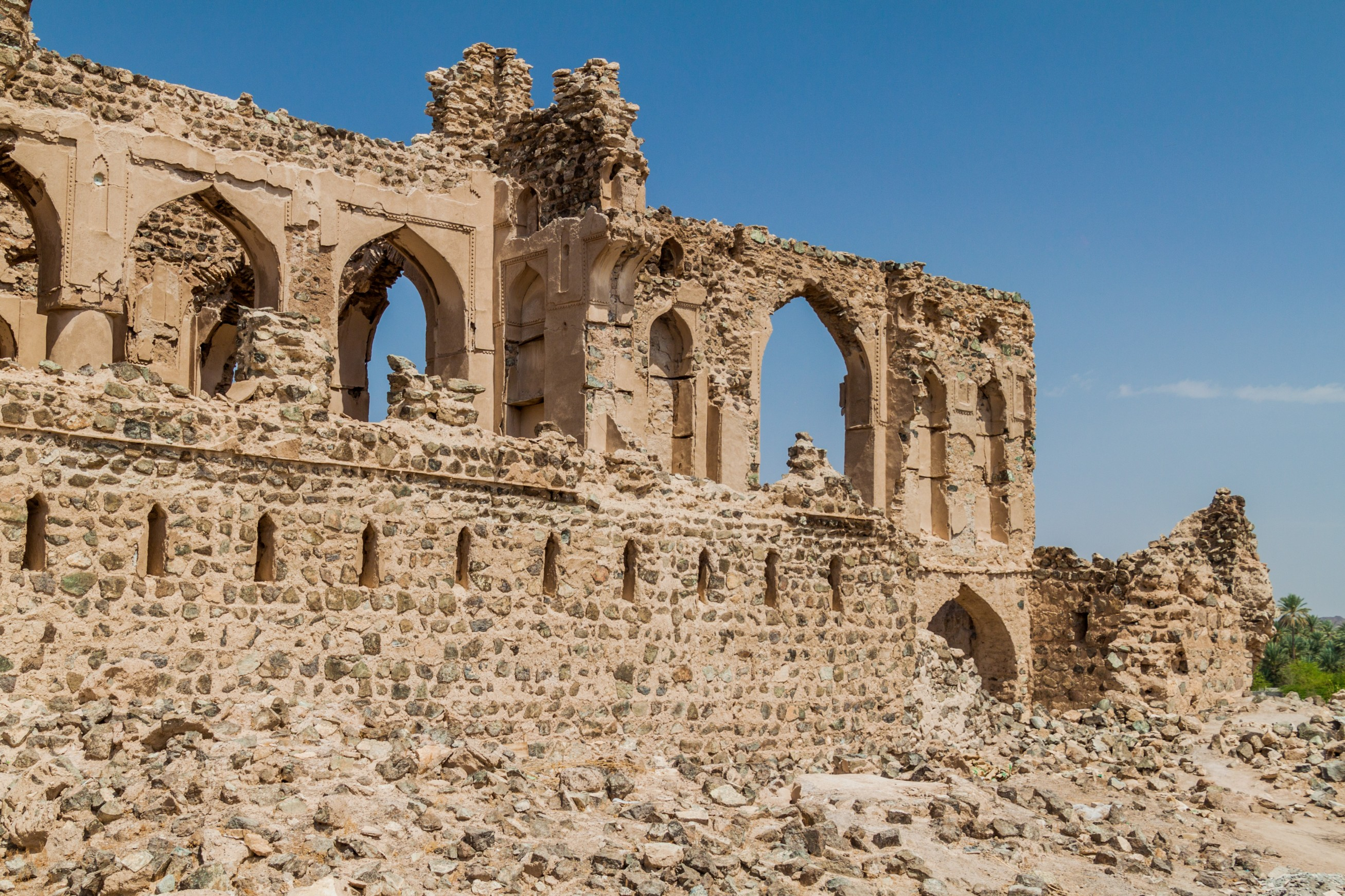 Ældgamle stenmure og ruiner i Ibra Old Quarter i Oman, en historisk seværdighed i ørkenlandskabet