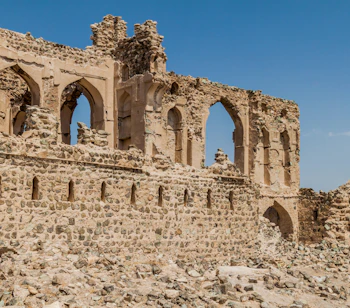 Ældgamle stenmure og ruiner i Ibra Old Quarter i Oman, en historisk seværdighed i ørkenlandskabet