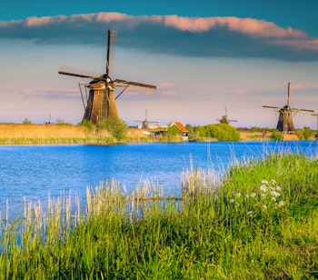 Ikoniske hollandske vindmøller ved Kinderdijk UNESCO verdensarvssted i solnedgangslys langs vandkanalen