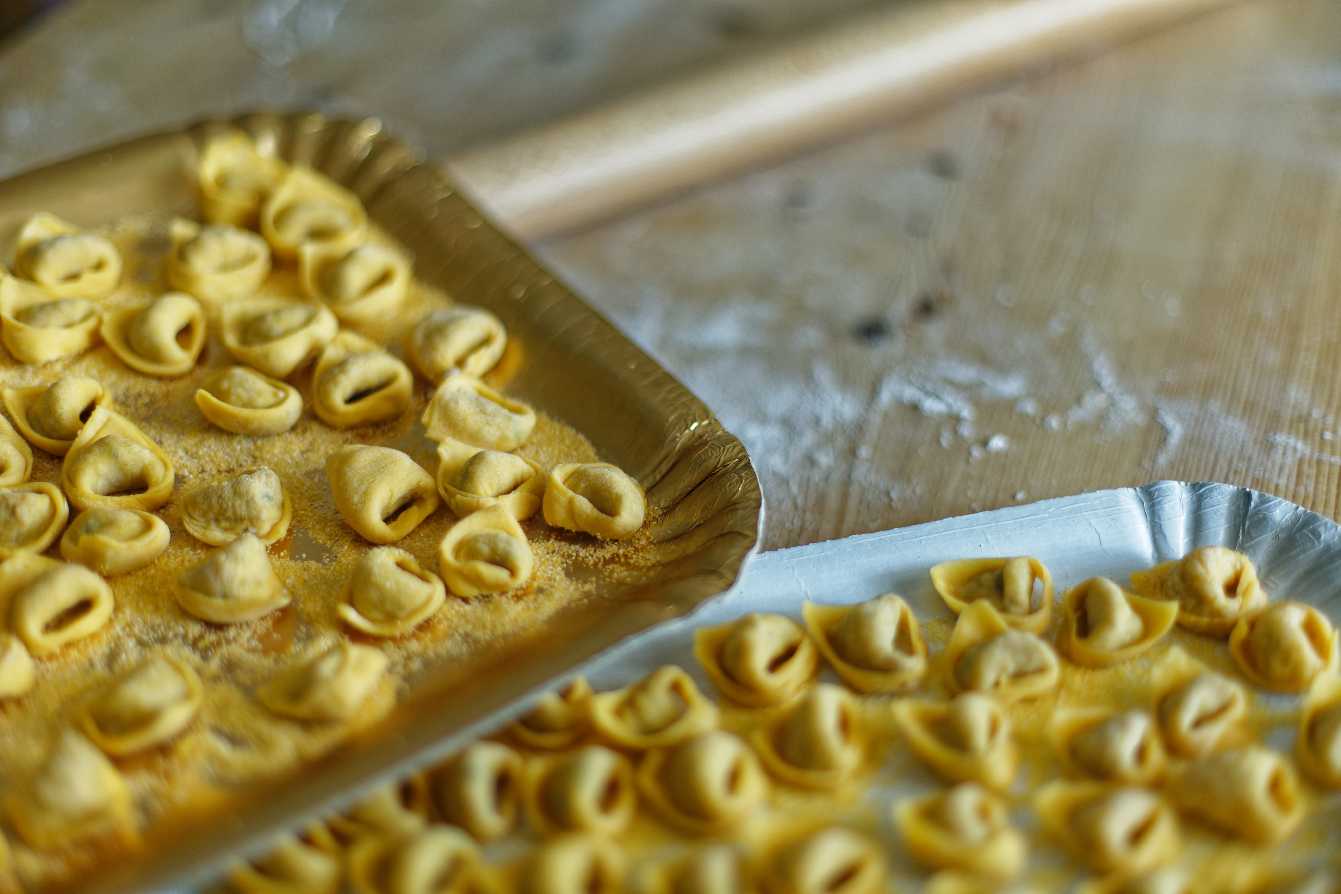 Traditionel italiensk cappelletti-pasta håndlavet på træbakker i Bologna, der viser den autentiske madkultur og pastakunst fra Emilia-Romagna regionen i Italien.