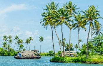 Traditionelt husbåd på Keralas rolige backwaters nær Alleppey i Sydindien - en unik oplevelse omgivet af vajende palmer og azurblå himmel i et tropisk paradis