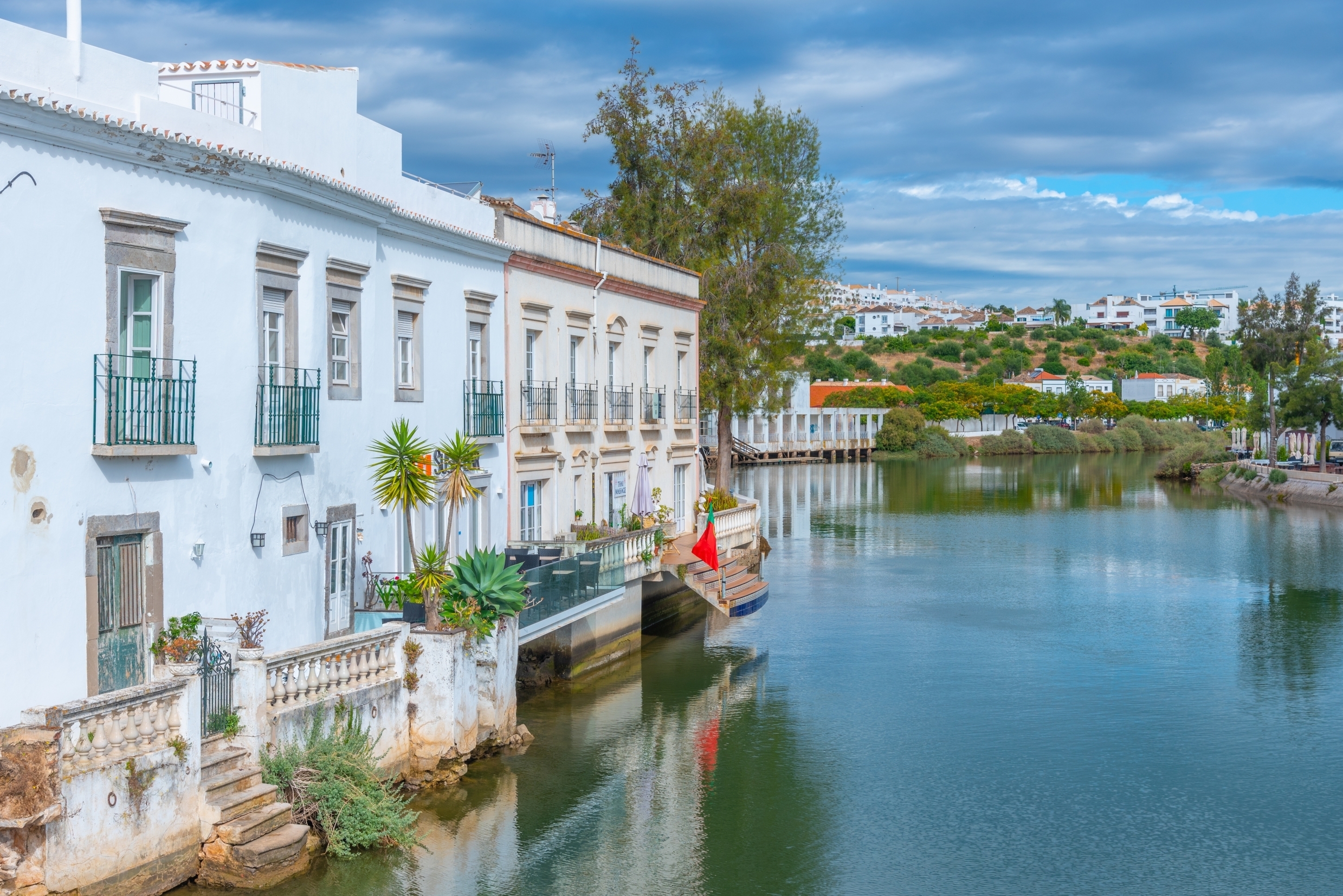 Huse ved Gilao-floden i Tavira, Portugal, med traditionel portugisisk arkitektur og en rolig flodbred.