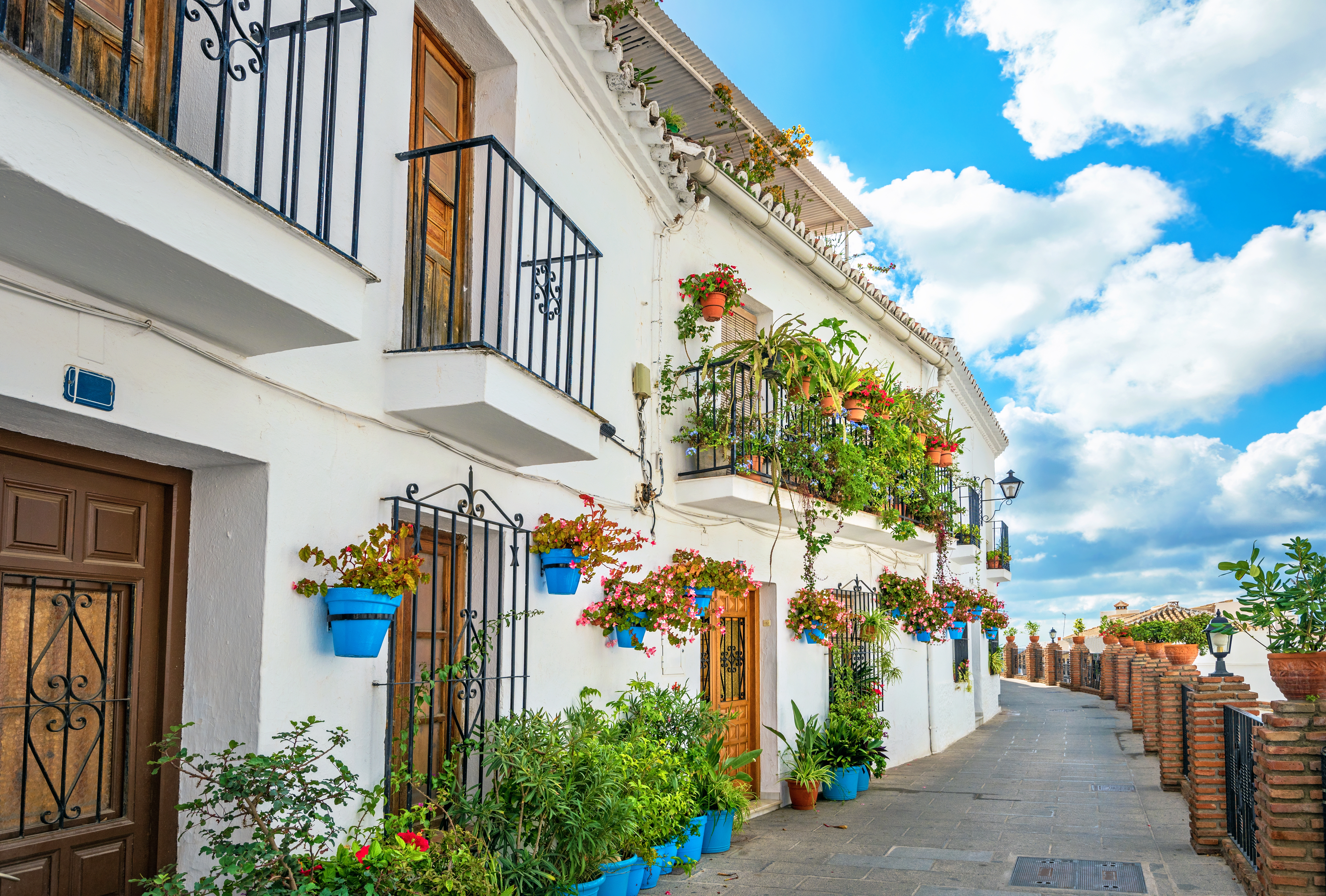 Malerisk smal gade med traditionelle hvide huse prydet med blå blomsterkrukker i Mijas landsby, Andalusien