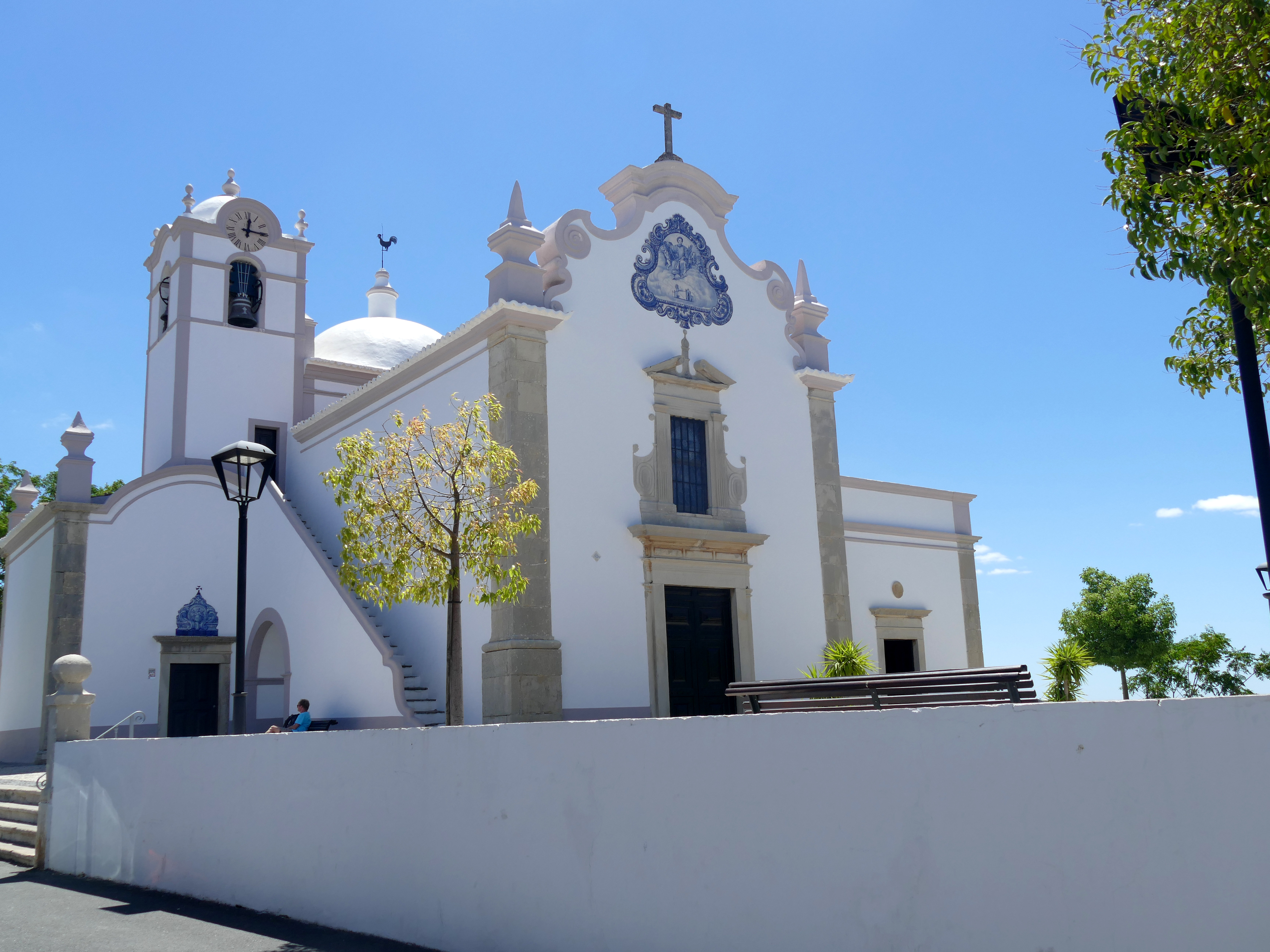 Smuk hvid kirke med karakteristiske blå fliser i Albufeira, Portugal. Traditionel portugisisk arkitektur under klar blå himmel i Algarve-regionen.