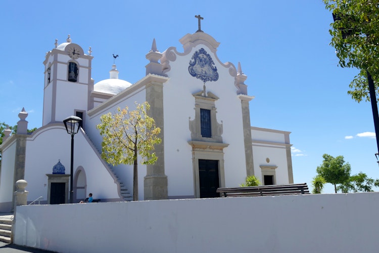 Smuk hvid kirke med karakteristiske blå fliser i Albufeira, Portugal. Traditionel portugisisk arkitektur under klar blå himmel i Algarve-regionen.