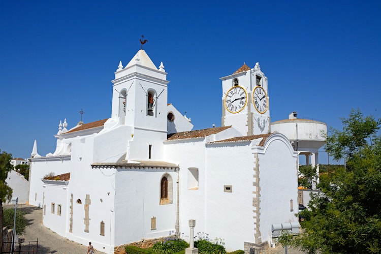 Hvid kirke med klokketårn og klokketårn i Tavira Portugal under blå himmel