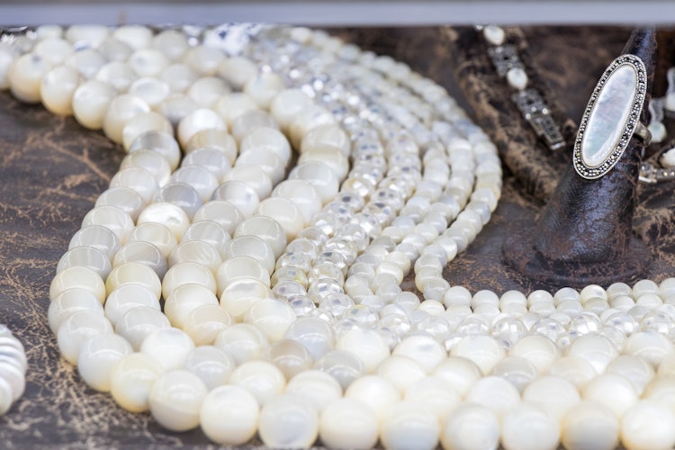 Traditionelle hvide perlekæder og smykker udstillet på træbord i Makedonien