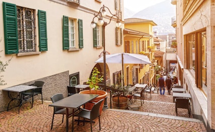 Hyggelig smal gade med udendørs caféer og restauranter i den historiske gamle bydel i Lugano, Ticino-kantonen, Schweiz