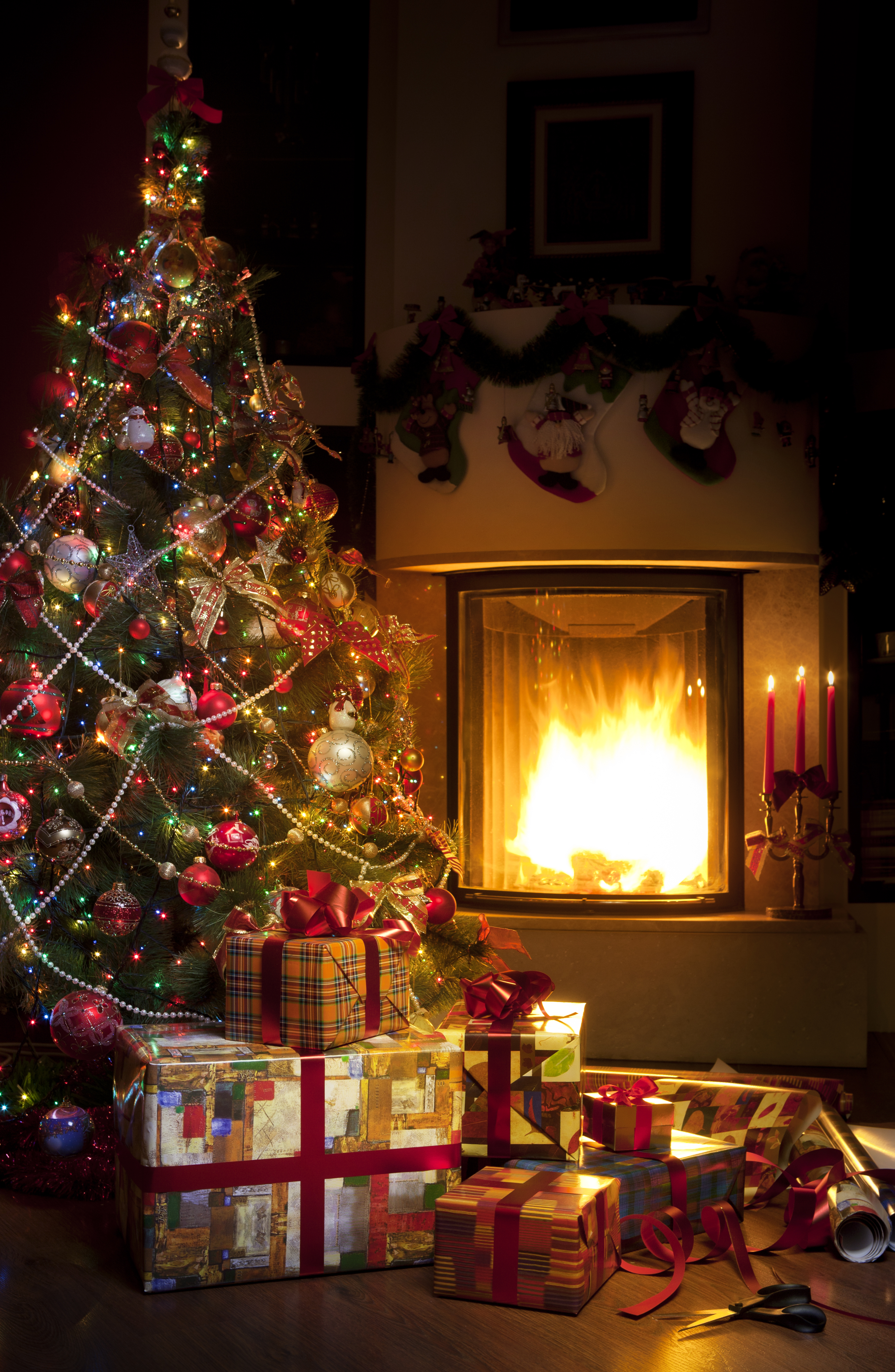 Hyggelig julestemning med pejs, juletræ og indpakkede gaver i varmt stuelys