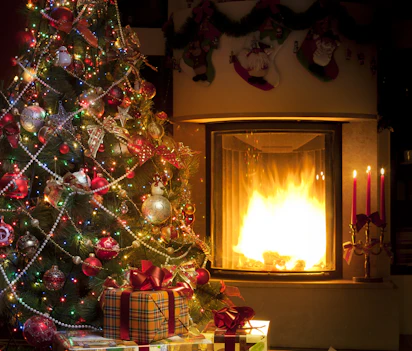 Hyggelig julestemning med pejs, juletræ og indpakkede gaver i varmt stuelys