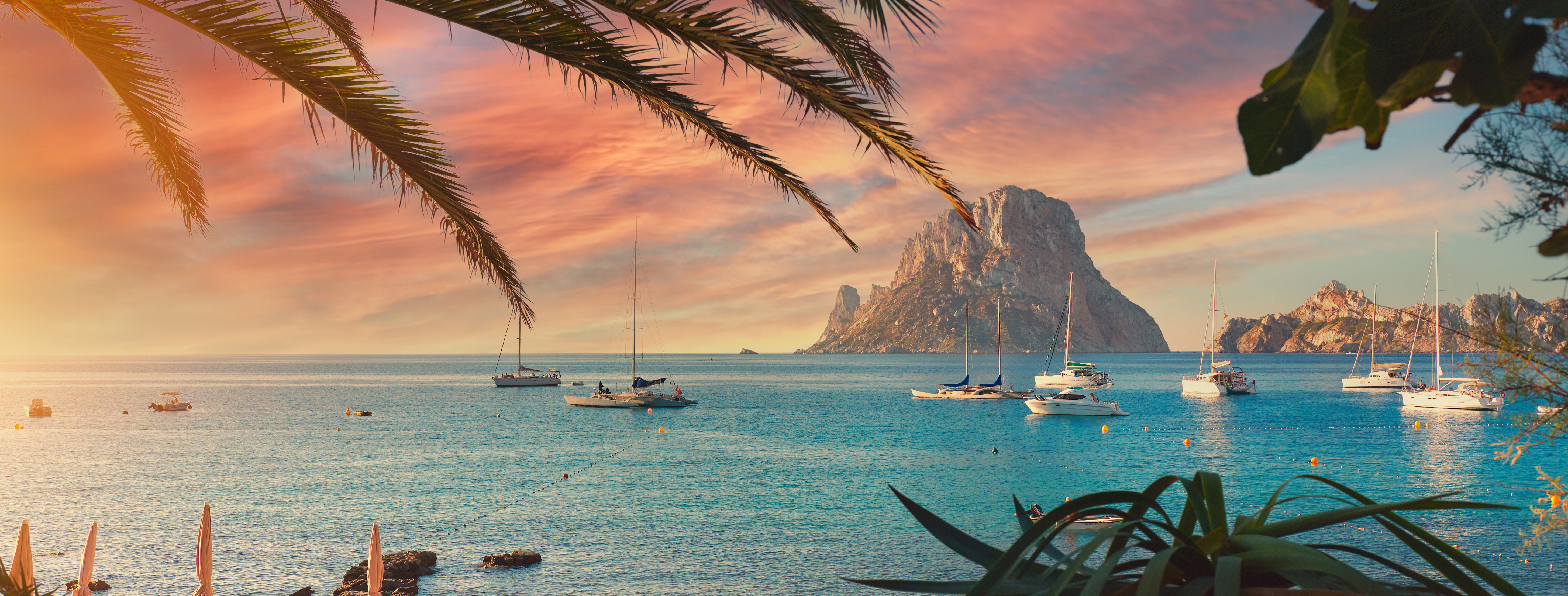 Spektakulær solnedgang over Es Vedra klippe med sejlbåde i turkisblåt middelhav, Ibiza Baleariske Øer