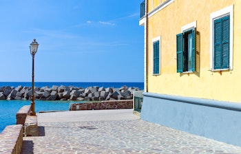 Charmerende lille havn i Santa Maria di Castellabate, Cilento, med traditionel gul bygning, stenmole og det skønne Middelhav