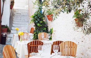 Hyggelig udendørs terrasse på en italiensk café i Peschici, Apulien, med hvide borde og smuk udsigt over det mediterrane landskab