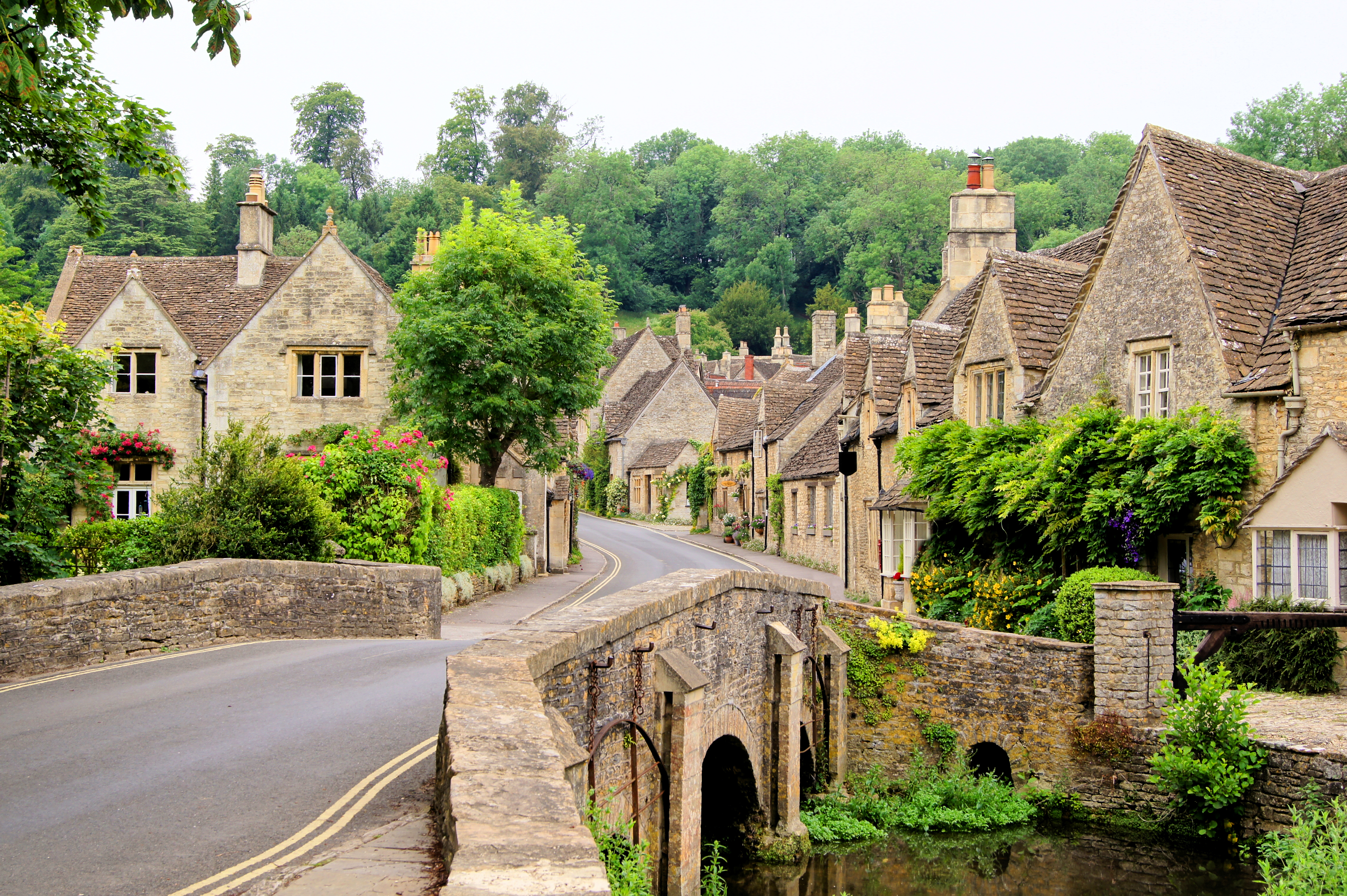 Charmerende stenhuse langs den idylliske gade i Castle Combe landsbyen i Cotswolds, England med traditionel arkitektur og bæk