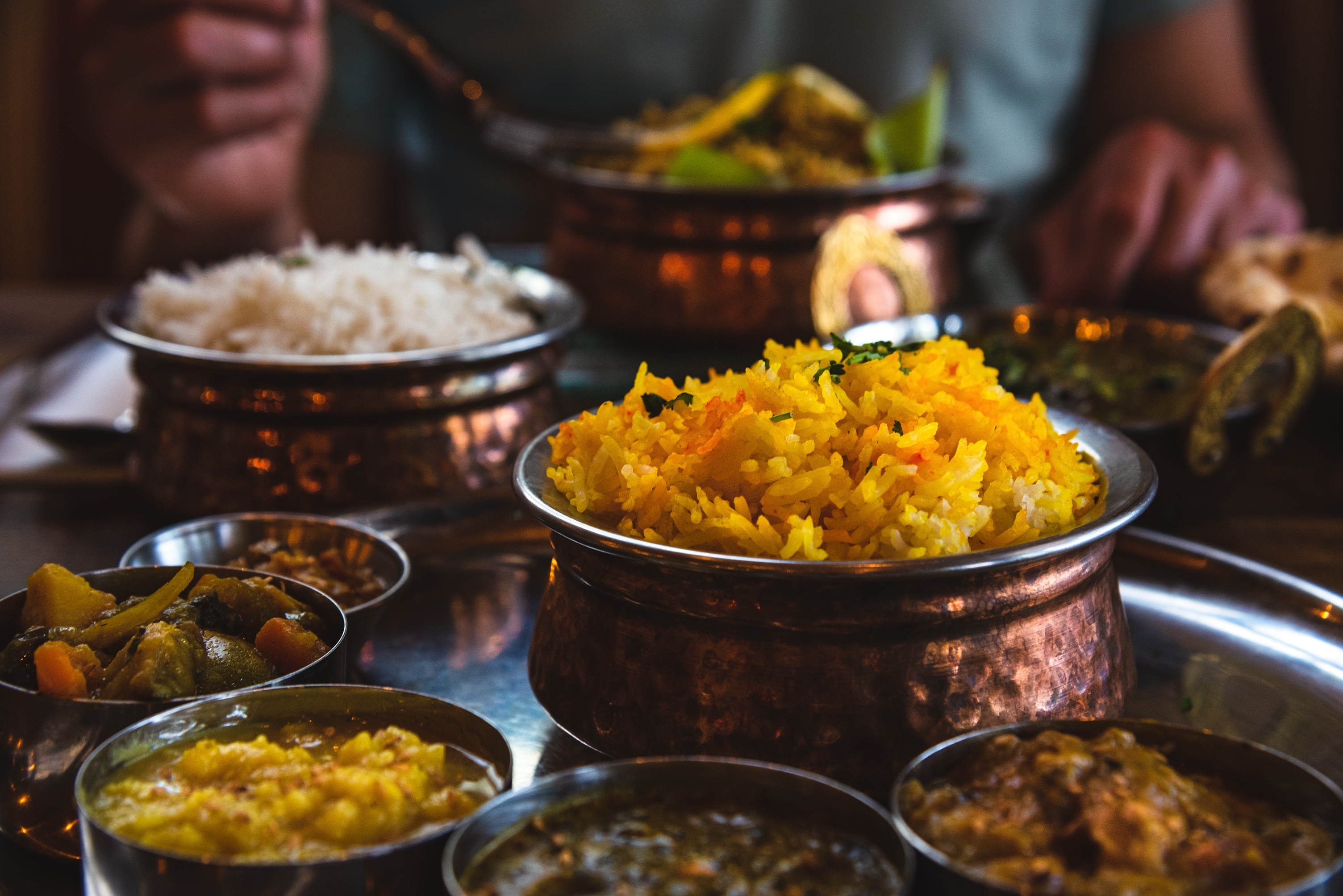 Person nyder et traditionelt indisk måltid med farverig vegetarisk thali, krydret kylling curry, ris og naan-brød i en autentisk restaurant - en kulinarisk rejseoplevelse i Indien