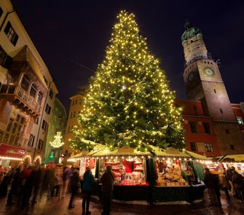 Stemningsfuldt julemarked i Innsbruck med det oplyste Gyldne Tag og pyntet juletræ i aftenmørket