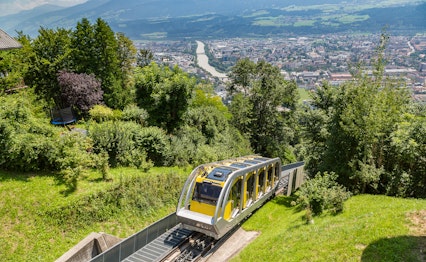 Den moderne Hungerburgbahn kabelbane der snor sig gennem de østrigske alper i Innsbruck på en klar sommerdag