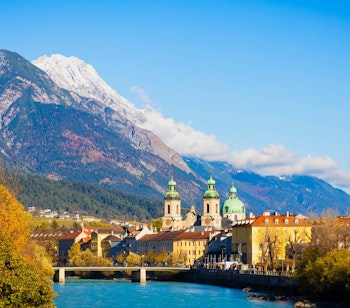 Betagende panoramaudsigt over Innsbruck bymidte med farverige historiske bygninger langs floden Inn omgivet af de majestætiske Tyroler-alper i Østrig