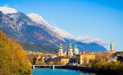 Betagende panoramaudsigt over Innsbruck bymidte med farverige historiske bygninger langs floden Inn omgivet af de majestætiske Tyroler-alper i Østrig