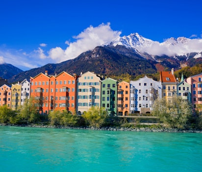 Panoramaudsigt over Innsbrucks farverige historiske bycentrum med floden Inn og de sneklædte Tyroler-alper i baggrunden