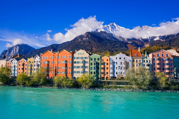 Panoramaudsigt over Innsbrucks farverige historiske bycentrum med floden Inn og de sneklædte Tyroler-alper i baggrunden
