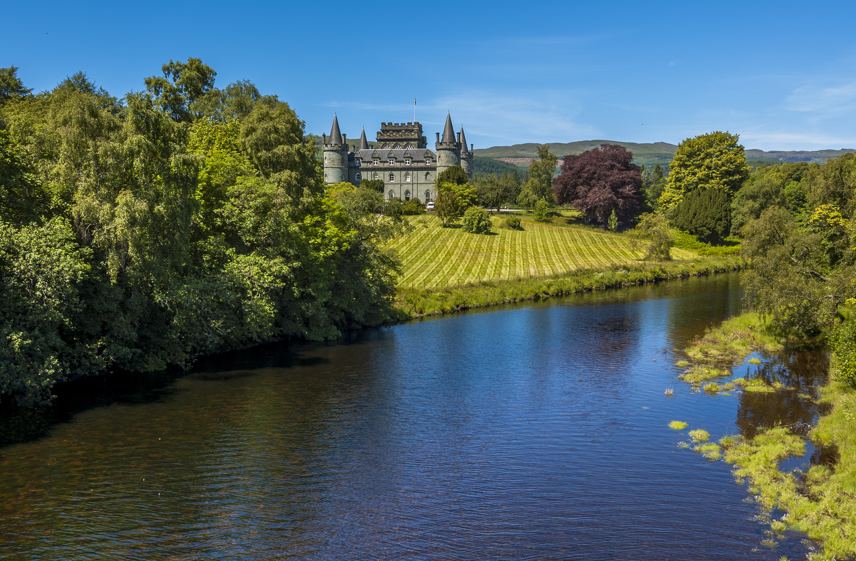 Inveraray Castle med gotisk arkitektur spejlet i Loch Fyne omgivet af grønne områder i Argyll, Skotland