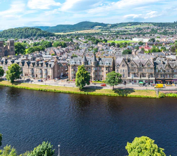 Panoramaudsigt over Inverness by langs floden Ness med historiske bygninger og skotske bjerge