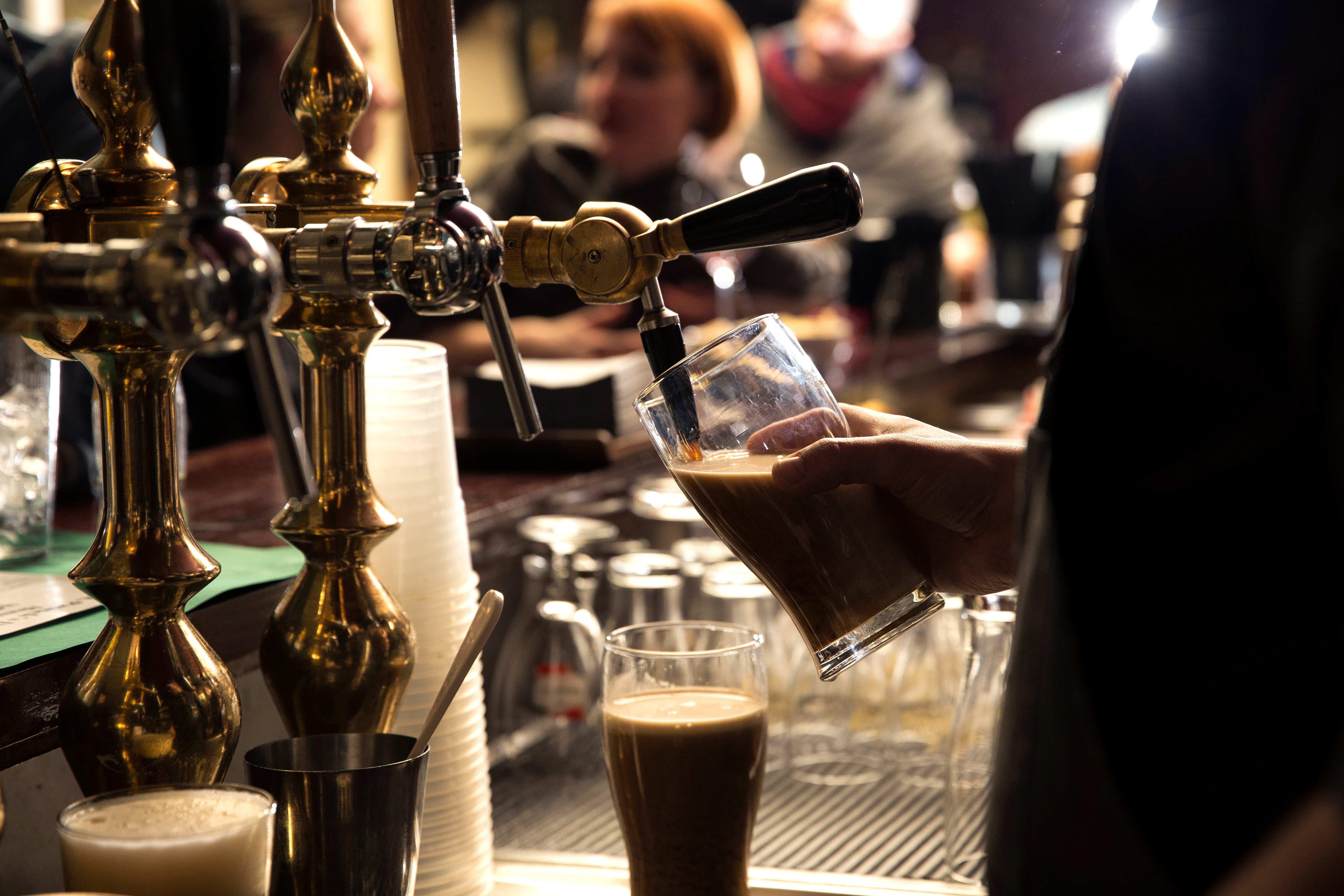 Bartender hælder en mørk irsk stout øl fra en traditionel messinghane på en irsk pub