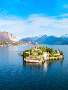 Betagende luftfoto af Isola Bella øen med det barokke palads og haver i Lago Maggiore søen, med Stresa by og de italienske alper i baggrunden