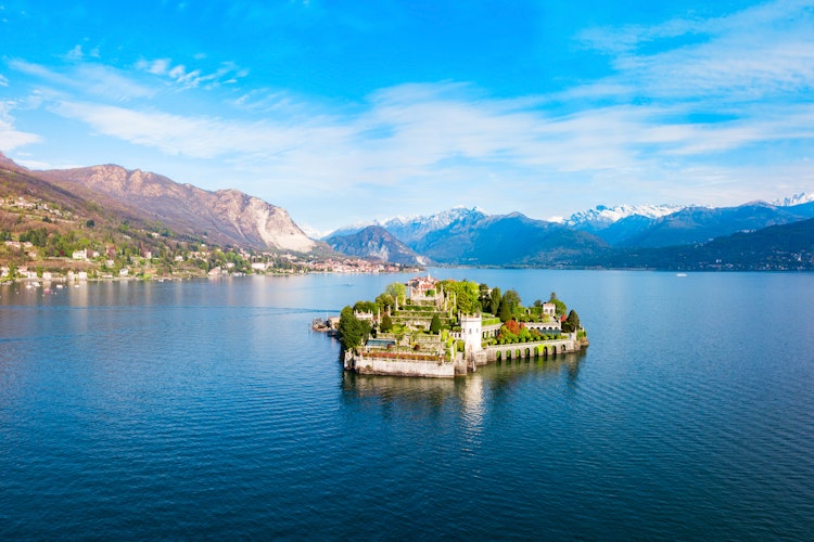 Betagende luftfoto af Isola Bella øen med det barokke palads og haver i Lago Maggiore søen, med Stresa by og de italienske alper i baggrunden