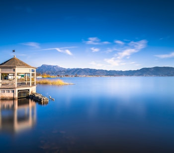 Træbro med gazebo på stille sø i Toscana Italien ved solnedgang