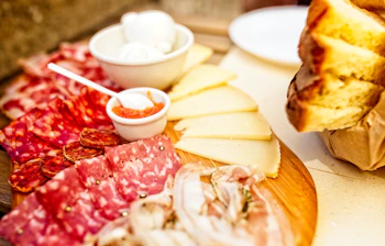 Traditionel italiensk antipasti tallerken med spegepølse, ost og friskt brød på restaurant