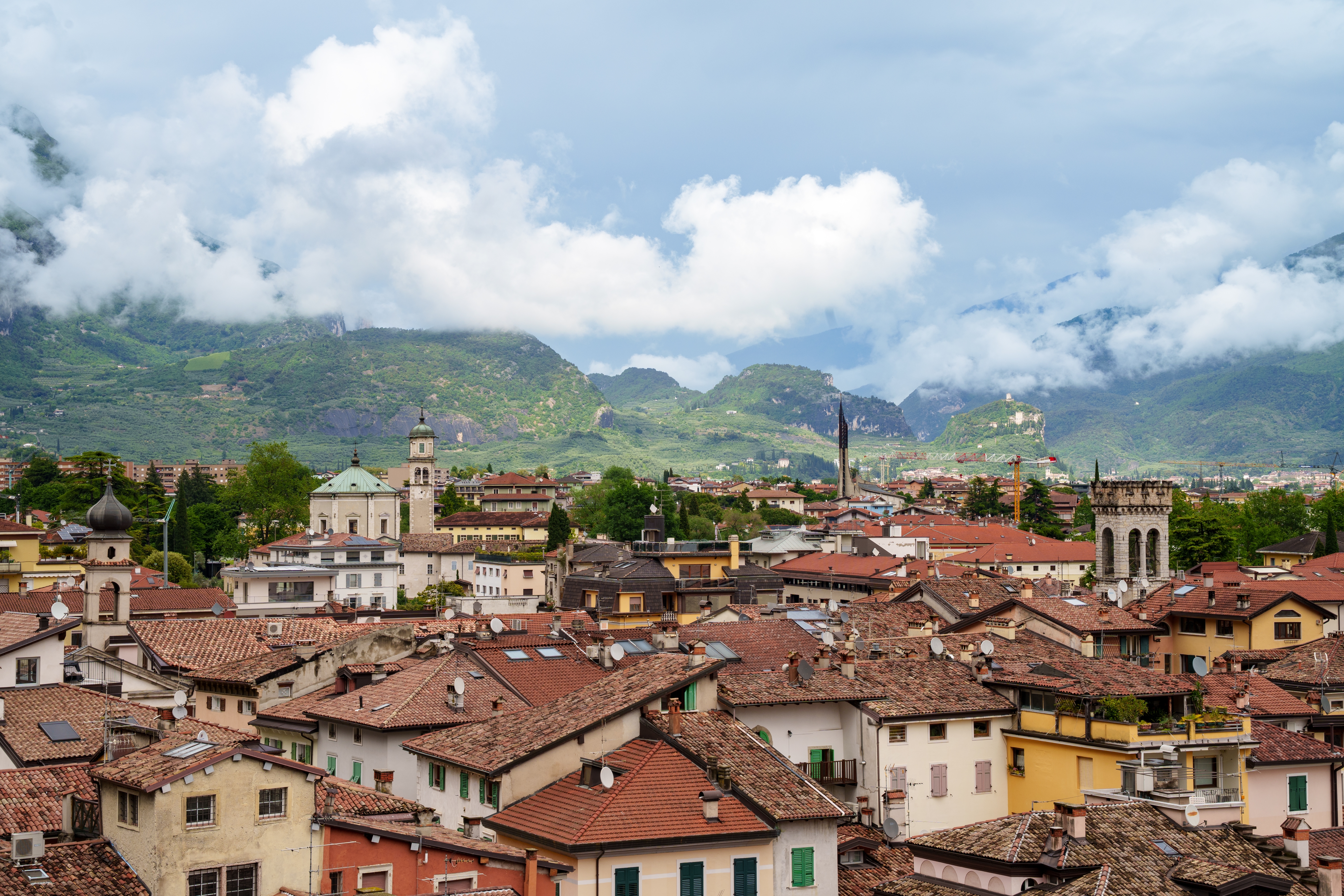 Malerisk udsigt over italiensk bjergby med røde tegltage og bjerge i baggrunden